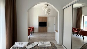 Une chambre d’hôtel moderne avec un grand lit, un téléviseur fixé au mur et un coin repas avec des chaises.