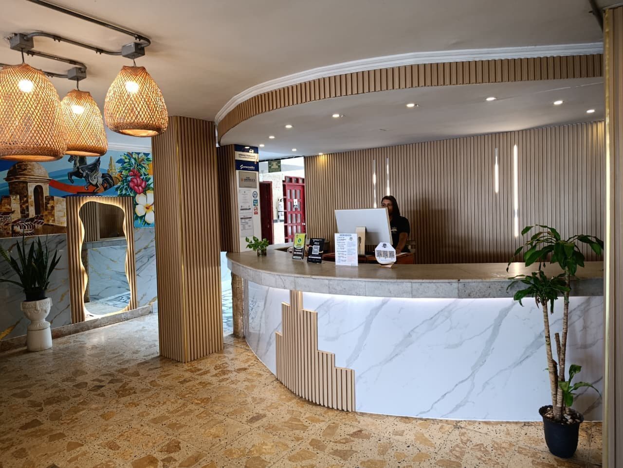 A reception area with a curved marble counter, wooden paneling, and a potted plant.
