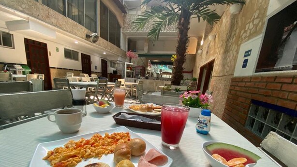A breakfast setting with a plate of food, a drink, and a fruit bowl. - Hotel Toledo FL (Cartagena)