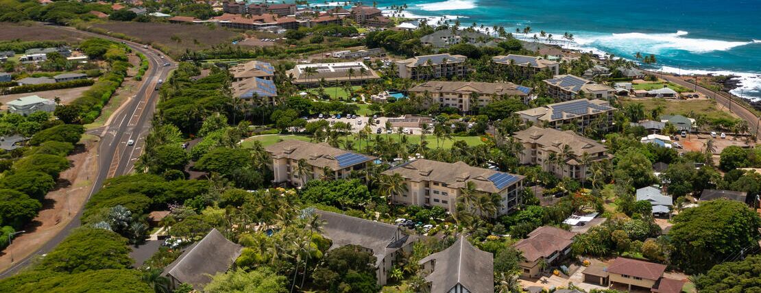 An aerial view of a coastal resort with multiple buildings, roads, and greenery.