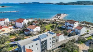 Uma área residencial costeira com edifícios modernos, um porto de iates e uma praia.