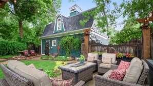 A backyard with a green house, wicker furniture, and a wooden fence. - Downtown, 6 kings, Sleeps 14+, Game Room,  Courtyard, Hot Tub (Colorado Springs)