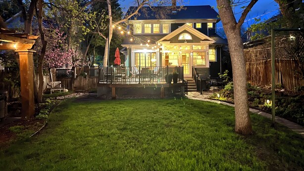 A well-lit house with a covered patio, a wooden deck, and a lawn. - Downtown, 6 kings, Sleeps 14+, Game Room,  Courtyard, Hot Tub (Colorado Springs)