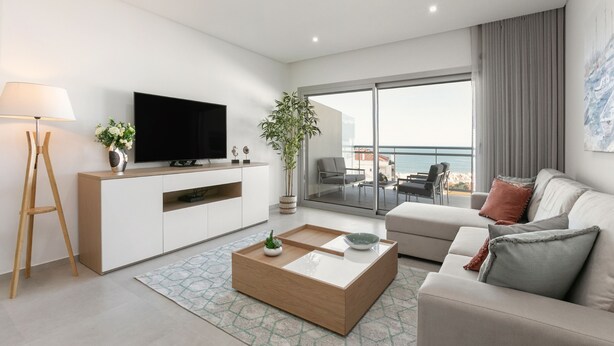 Un salon moderne doté d’un téléviseur à écran plat, d’une table basse en bois, d’un canapé et d’un balcon offrant une vue sur la mer.