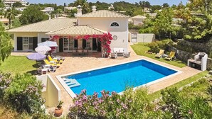 A residential property with a swimming pool, outdoor seating, and lush greenery. - Attractive Family Villa, A/C, Private Pool - 5mins drive to the Iconic Beach at Praia da Marinha! (Lagoa)