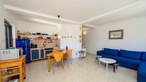 A compact living space with a kitchenette, a dining area, a blue sofa, and a small table. - 3 bedroom beautiful apartment in Klek (Klek)