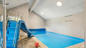 Ein Swimmingpool mit einer blauen Rutsche und einem roten Ball auf dem Boden.