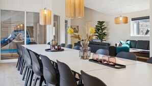 Ein moderner Essbereich mit einem langen Tisch, schwarzen Stühlen und Pendelleuchten.