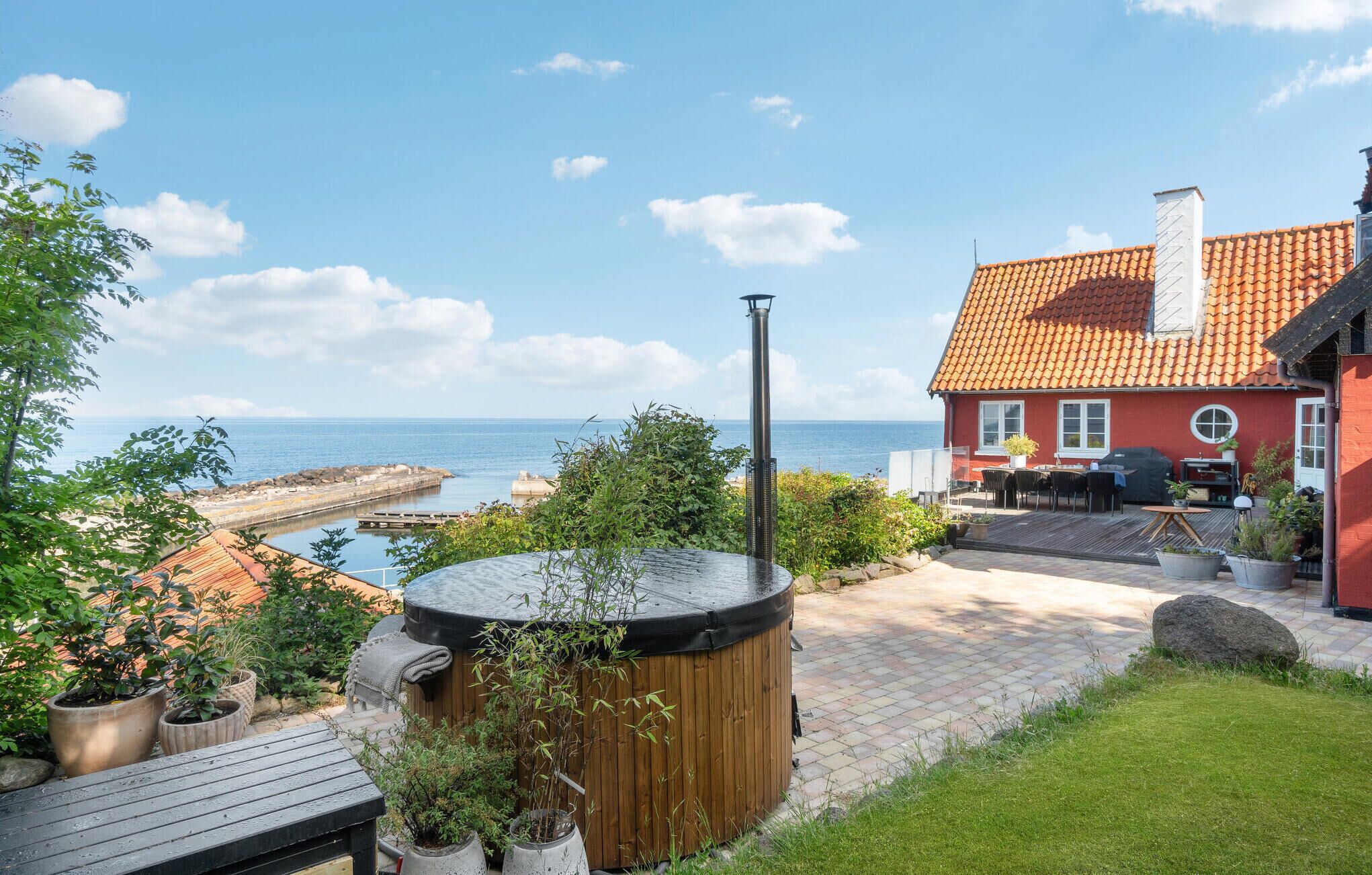 Une propriété située en bord de mer, dotée d’une terrasse en bois, d’un jacuzzi et offrant une vue sur l’océan.