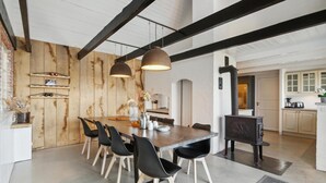 Un espace de repas moderne avec un mur d’accent en bois, des chaises noires et des luminaires suspendus.