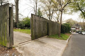 Ein hölzernes Tor mit einem Betonweg, der zu einer Wohnstraße führt.