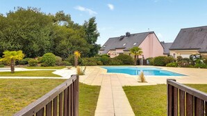A backyard with a swimming pool, surrounded by a wooden fence, and houses in the background. - Amazing home in Erquy with heated swimming pool (Erquy)