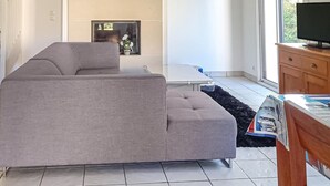 A living room with a grey sofa, a small table, a TV, and a fireplace. - Amazing home in Erquy with heated swimming pool (Erquy)