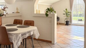 A dining area with a table set for four, a clock, and potted plants. - Gorgeous home in Hemmet with WiFi (Hemmet)