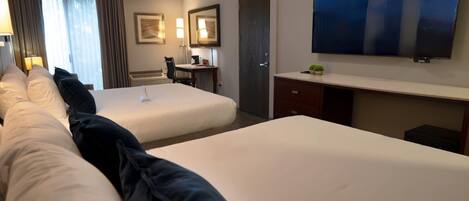 Una habitación de hotel con dos camas, un escritorio, una silla, un televisor y una puerta.