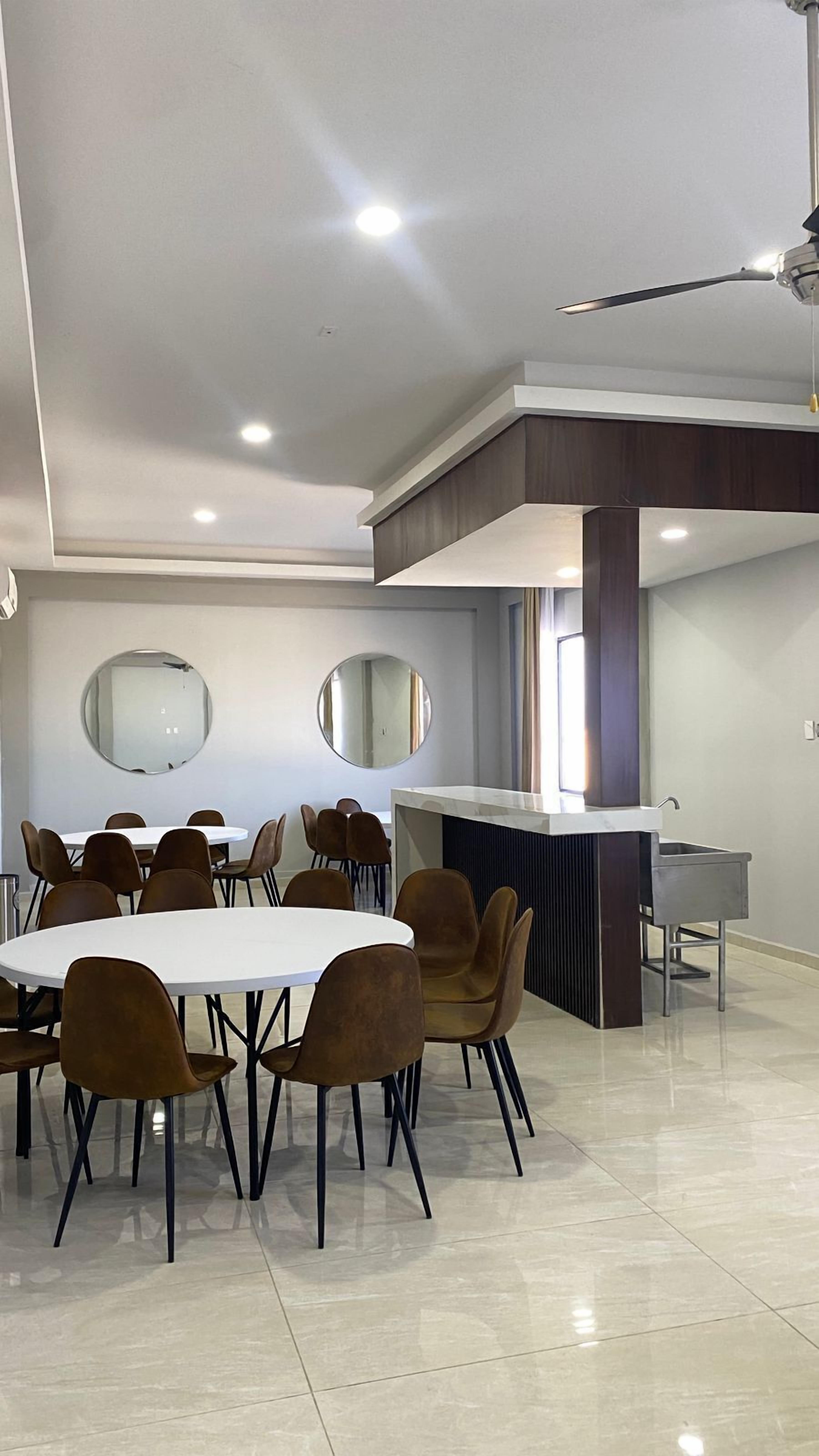 Un comedor moderno con una mesa redonda y sillas, una barra de cocina y un espejo grande en la pared.
