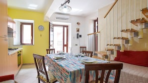A dining area with a table set for four, chairs, a clock, and a staircase with wooden steps. - Gorgeous home in Roccalumera with WiFi (Roccalumera)