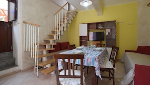 A dining area with a wooden staircase, a dining table set with plates and glasses, and a television on a shelf. - Gorgeous home in Roccalumera with WiFi (Roccalumera)