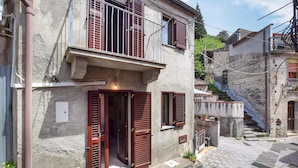 A two-story building with wooden shutters, a balcony, and a stone facade. - Gorgeous home in Roccalumera with WiFi (Roccalumera)