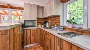 Una cocina compacta con gabinetes de madera, microondas integrado, un lavamanos y una ventana con vistas a la vegetación.