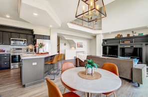 A modern kitchen with stainless steel appliances, a dining area with a round table and chairs, and a cozy living space with a sofa and a fireplace. - Creekside Mountain View Retreat, Hot Tub, Sleeps 14, 6 Kings, 5 bathrooms (Colorado Springs)