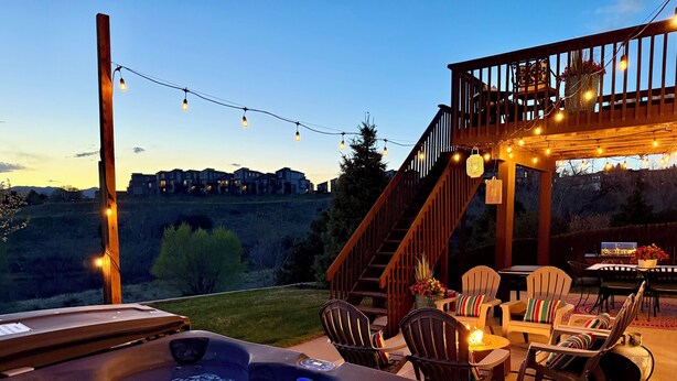 A hot tub with a wooden deck, outdoor furniture, and string lights. - Creekside Mountain View Retreat, Hot Tub, Sleeps 14, 6 Kings, 5 bathrooms (Colorado Springs)
