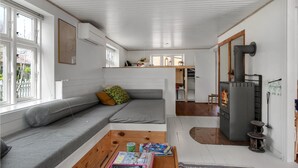 Een gezellige woonkamer met een bank, een salontafel met tijdschriften, een open haard en grote ramen.