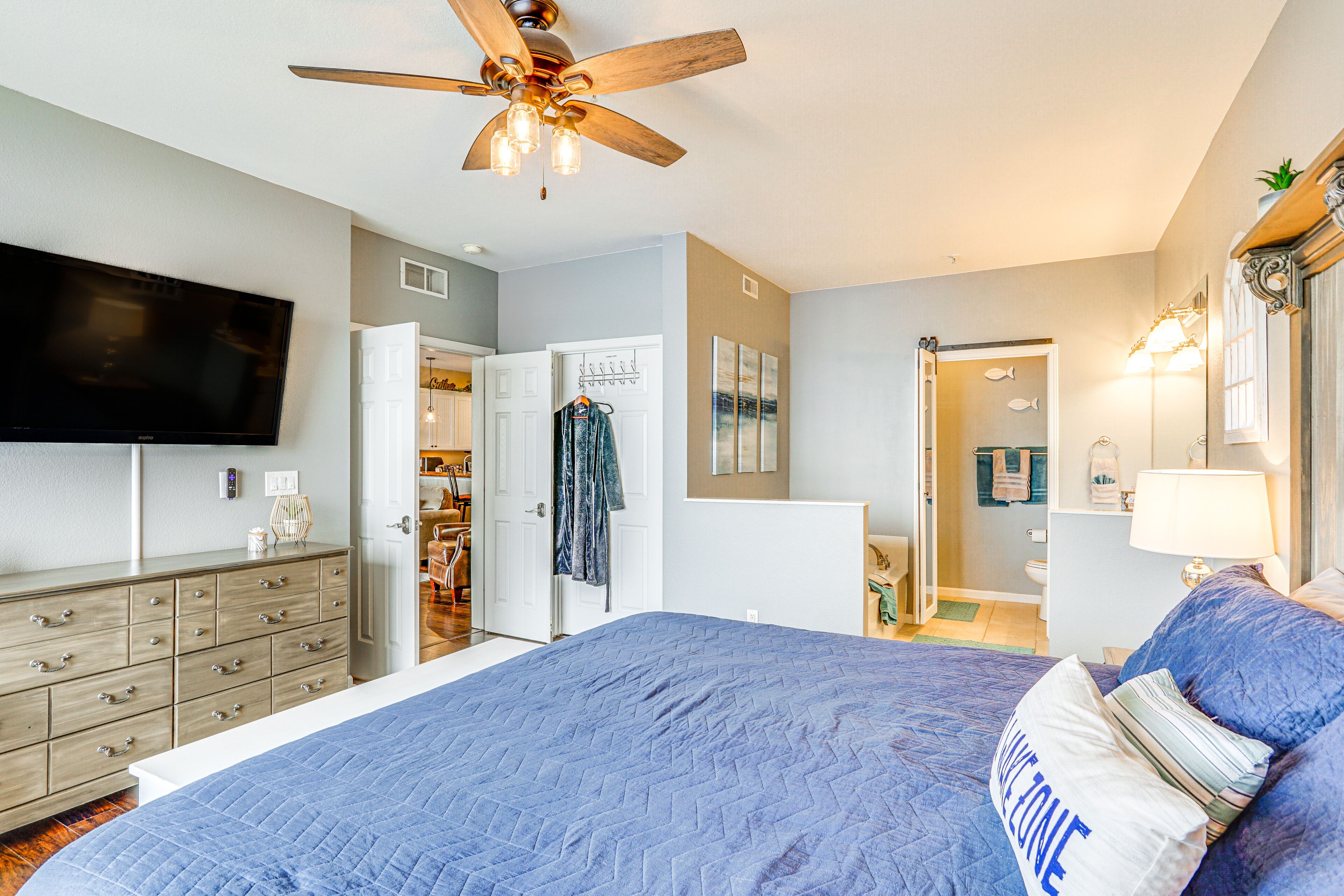 A bedroom with a large bed, a ceiling fan, a TV, a dresser, and a closet.