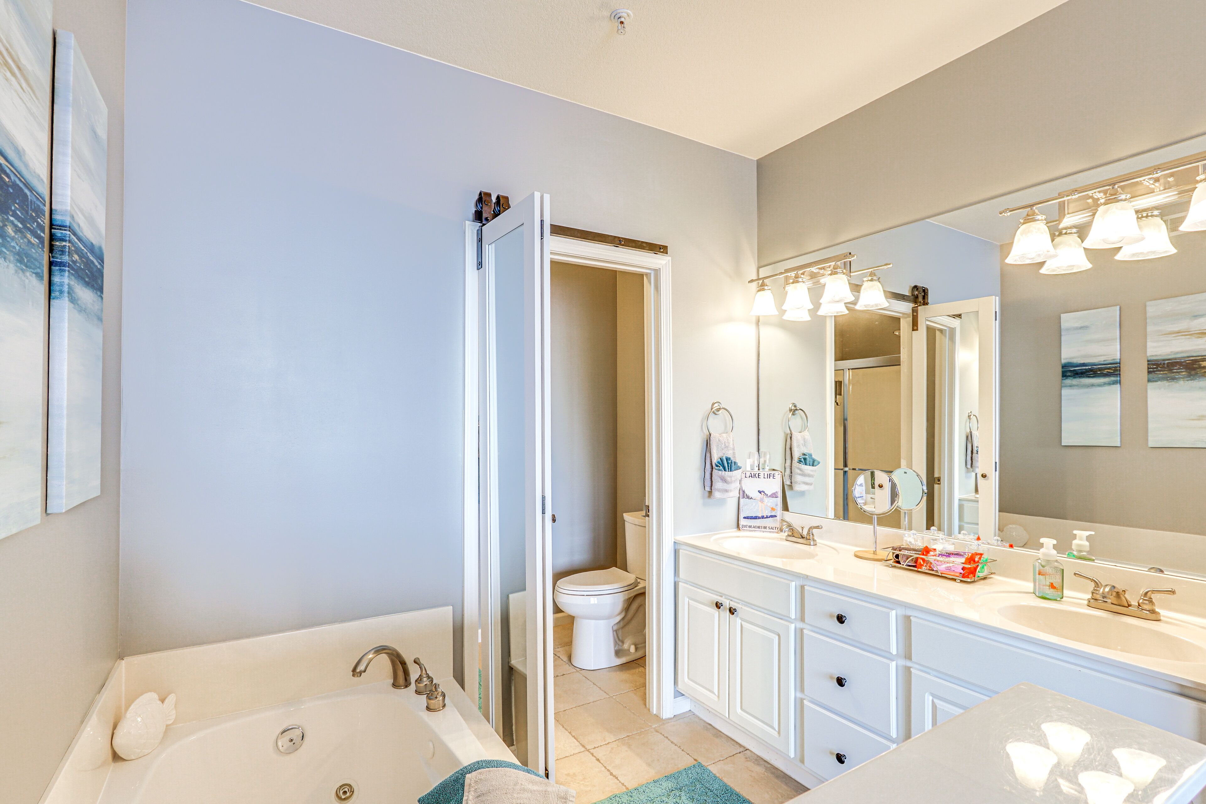 A modern bathroom with a white sink, vanity, and a large mirror.