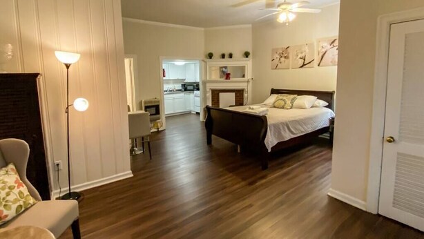 Une chambre à coucher avec un lit, une chaise, une lampe sur pied et une cheminée.