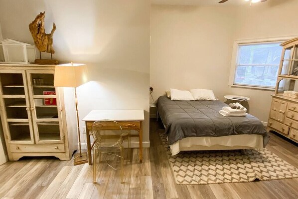 A bedroom with a bed, bedside table, lamp, and a wooden cabinet. - Stylish Studio Apartment in Downtown Lexington (Lexington)