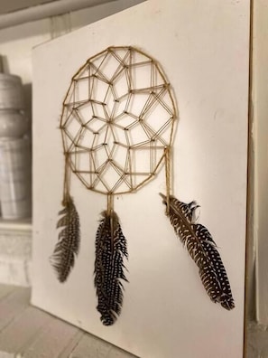 A geometric dreamcatcher with feathers hanging from it, displayed on a white wall. - Stylish Studio Apartment in Downtown Lexington (Lexington)