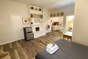 Ein kleines Hotelzimmer mit Bett, einer Küchenzeile, einem Kamin und einem Essbereich.