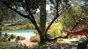 A hammock under a tree by a pool with a view of a hilly landscape. - La Jara Gaucín by Ruralidays (Málaga)