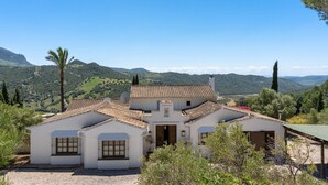 A white villa with a tiled roof, surrounded by greenery and hills. - La Jara Gaucín by Ruralidays (Málaga)