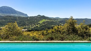 A swimming pool with a view of a mountain range and dense vegetation. - La Jara Gaucín by Ruralidays (Málaga)