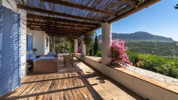 A covered outdoor seating area with wicker furniture and a view of a mountainous landscape. - La Jara Gaucín by Ruralidays (Málaga)