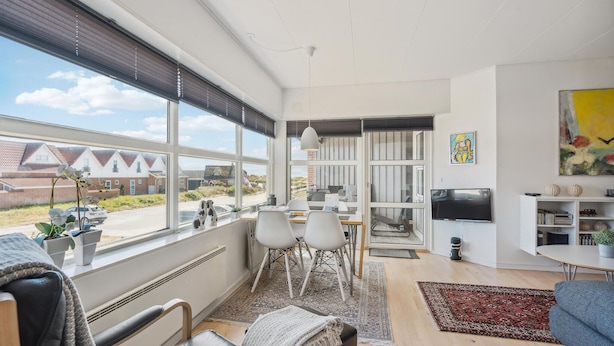A spacious living room with a large window, a dining area, and a TV mounted on the wall. - Nice apartment in Fanø with WiFi (Fanø)