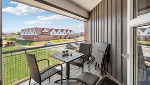 A balcony with a table and chairs, a view of houses, and a fence. - Nice apartment in Fanø with WiFi (Fanø)