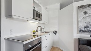 A compact kitchen with a microwave, stove, and sink. - Nice apartment in Fanø with WiFi (Fanø)