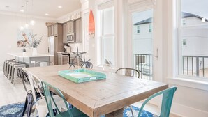 A modern kitchen with a long dining table, built-in appliances, and large windows. - Coral Sunset: Free golf cart, 2min to beach, Heated pool steps away, Bunk rooms (Miramar Beach)