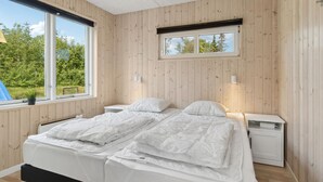 Une chambre à coucher avec un lit double, deux tables de chevet, une fenêtre et une petite lucarne.