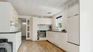 Une cuisine de taille réduite avec des meubles blancs, un four encastré et un réfrigérateur.