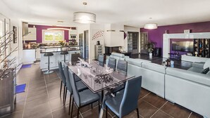 A modern kitchen with a dining area, featuring a glass table, bar stools, and a built-in oven. - Nice home in Sérignan (Sérignan)