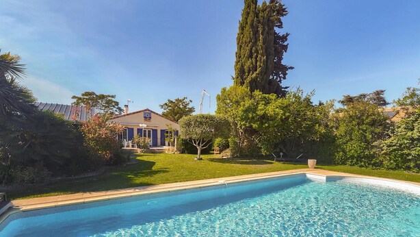 A swimming pool with a clear blue water surface, surrounded by a well-maintained lawn and various trees. - Nice home in Sérignan (Sérignan)