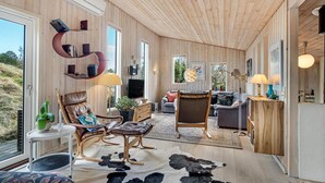 A spacious room with a large window, a leather sofa, a wooden coffee table, and a cowhide rug.