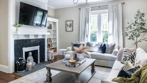 Un salon avec une cheminée, un téléviseur et un lustre.