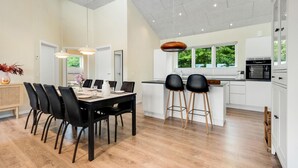 Una cocina moderna con una isla central, sillas negras y una mesa de comedor con sillas.