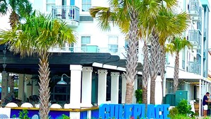 Un hôtel à plusieurs étages, doté de balcons, d’un espace extérieur couvert aménagé en coin salon et d’une enseigne indiquant le mot « GULF ».