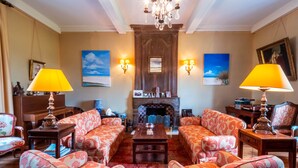A traditional living room with patterned sofas, a fireplace, and wall-mounted lamps. - Demeure Historique - Village D'agon - 800m de la Plage (Agon-Coutainville)